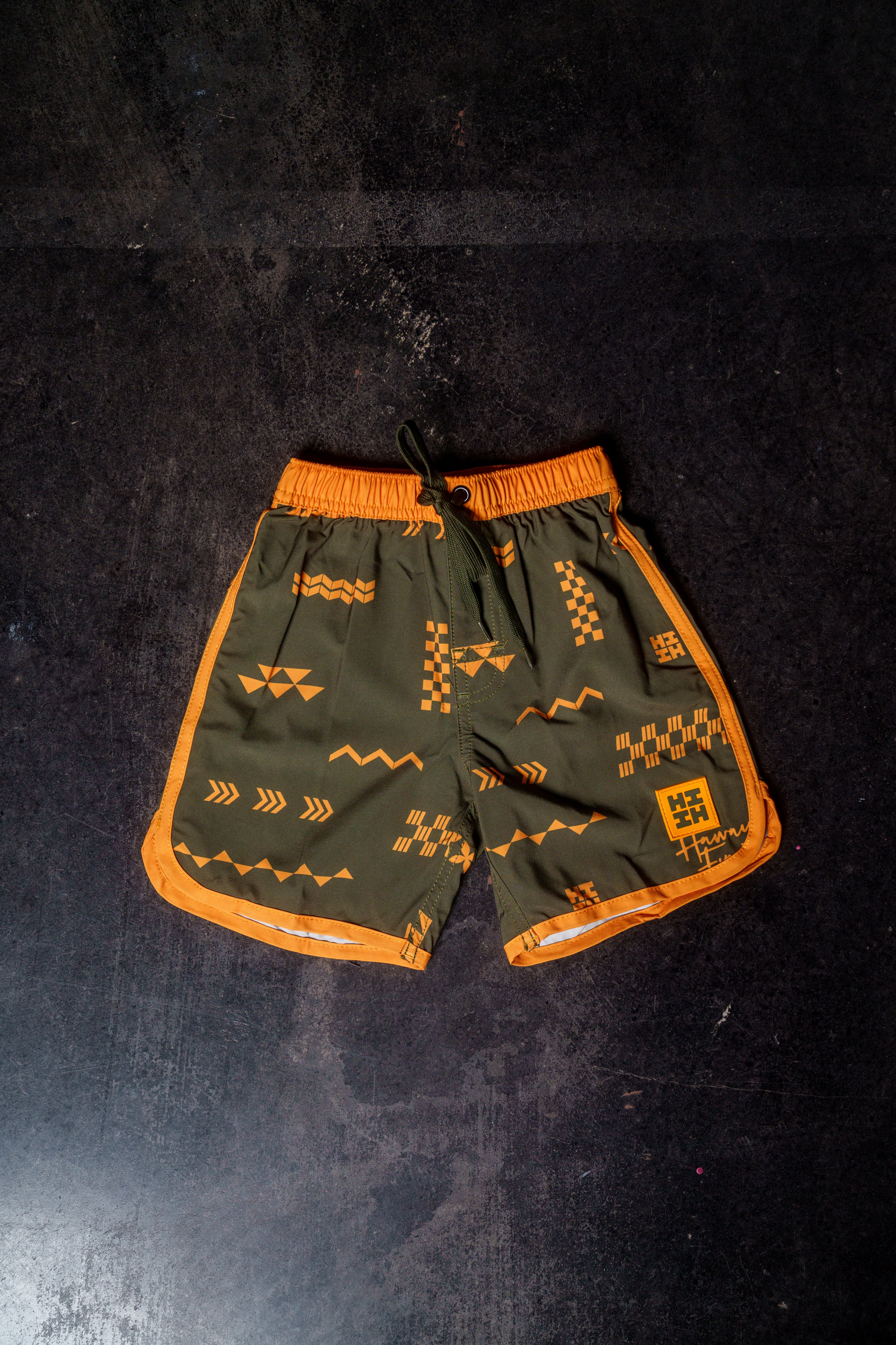 ʻANO KĀPALA KEIKI OLIVE & ORANGE BOARDSHORTS